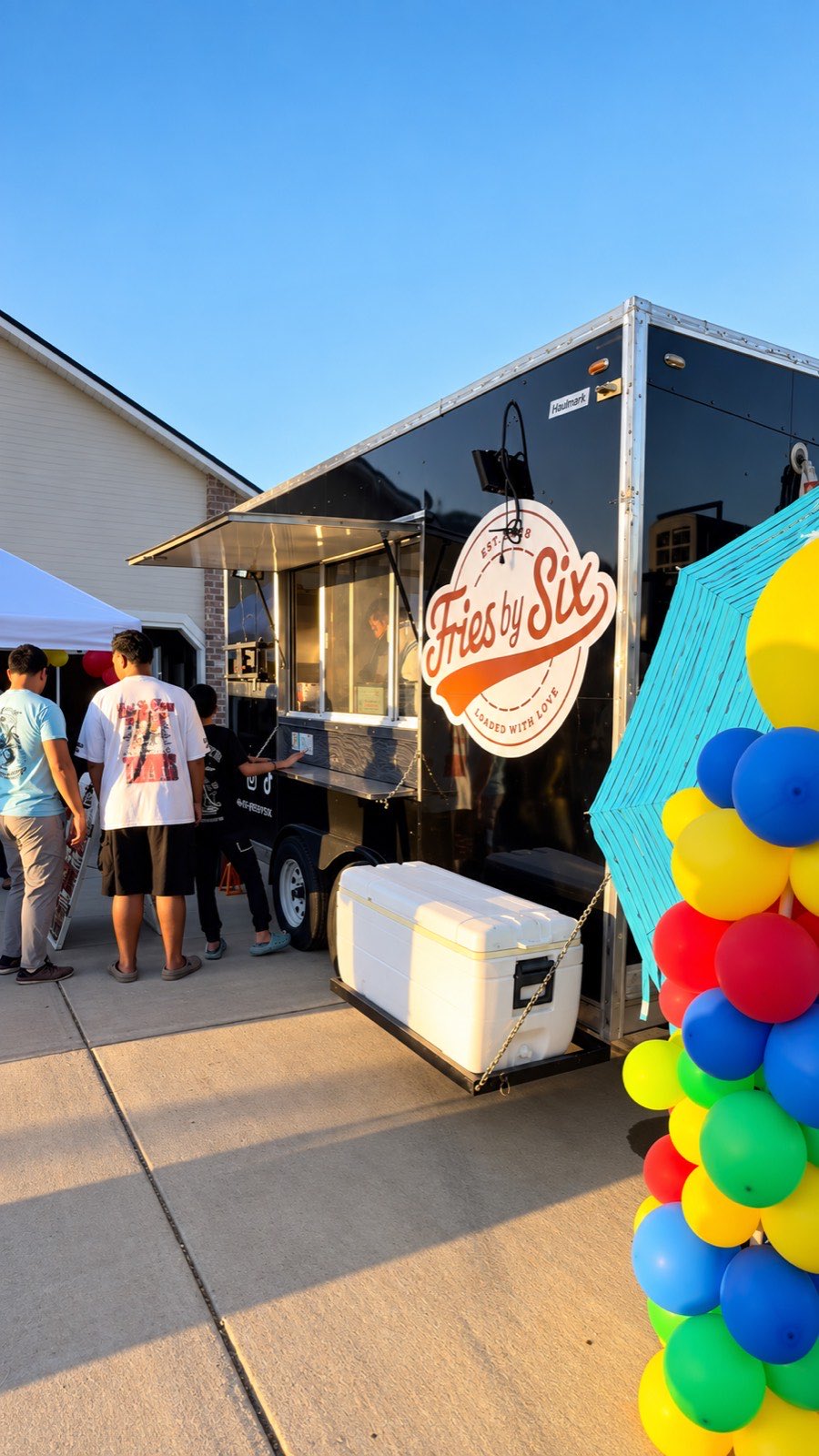 Fries by Six food truck at a private event with a line of guests and a balloon arch beside the service window.