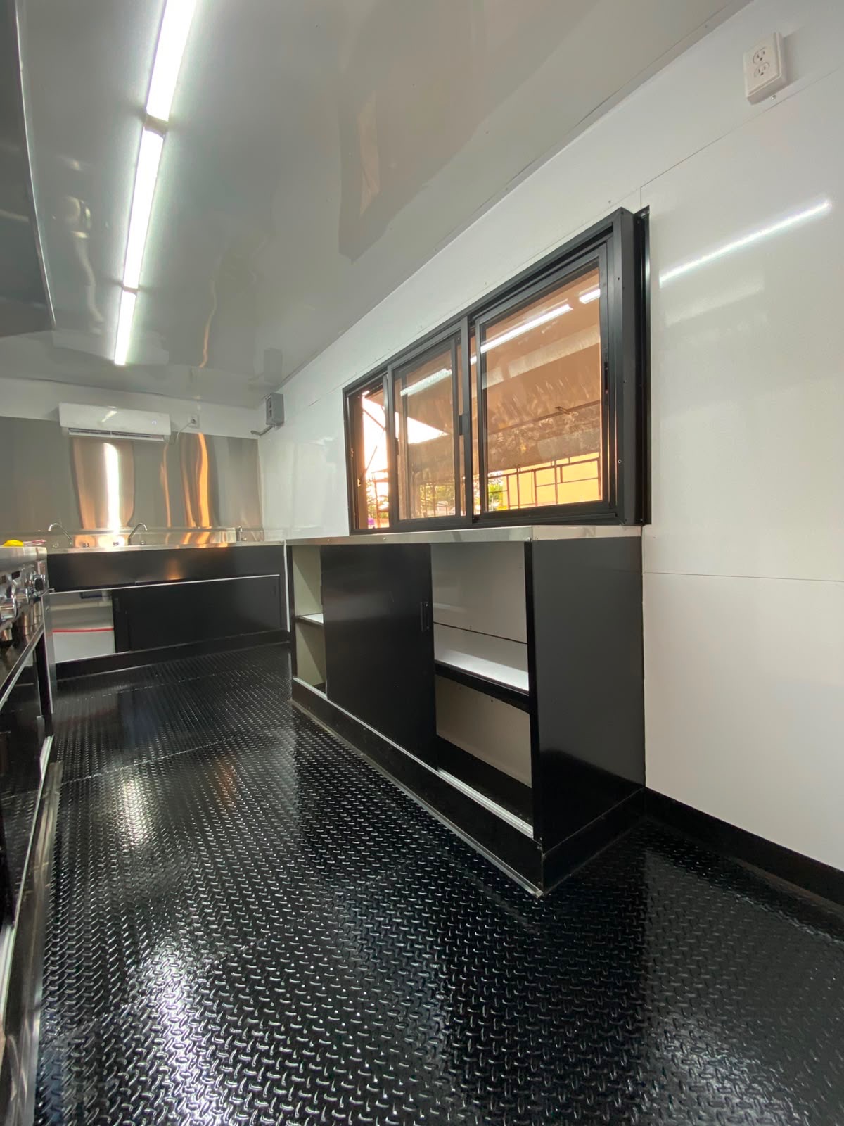 Prep and storage side of the galley: under-counter cabinets, stainless sinks and the service window from inside.